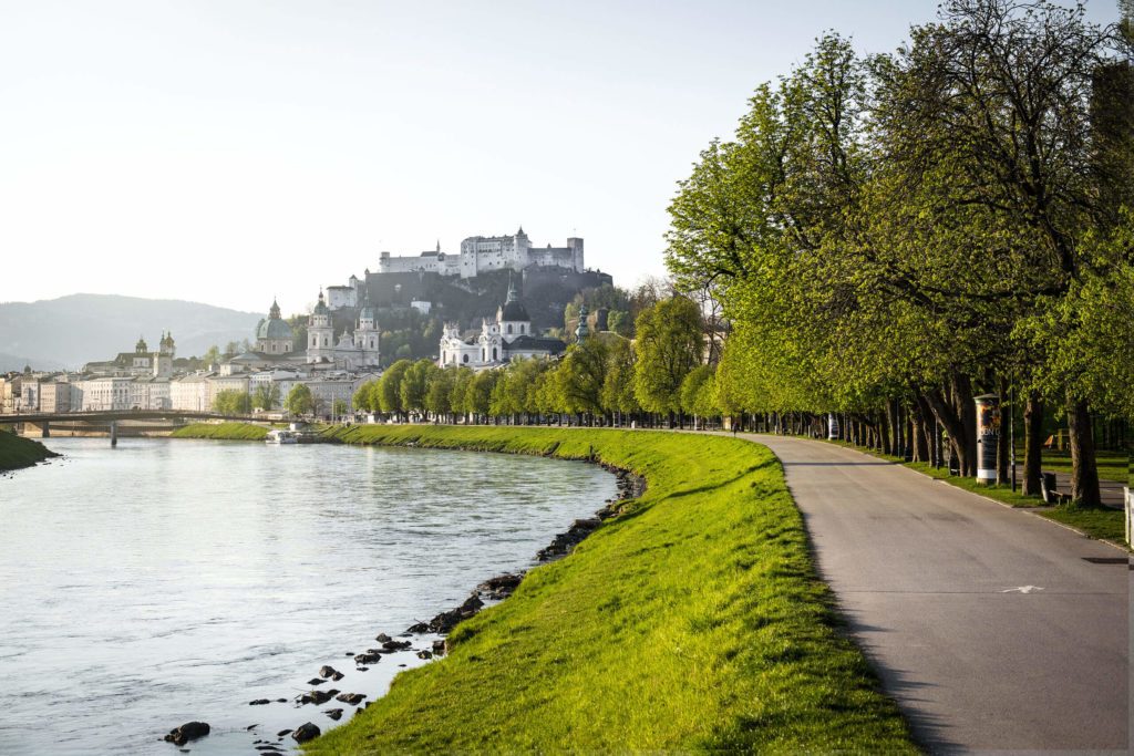 Geh- und Radweg entlang der Salzach, dahinter erhebt sich die Altstadt Salzburgs